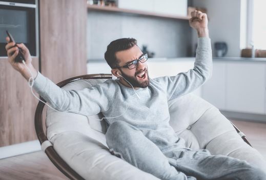 close up. happy man enjoying his favorite music while sitting in a chair