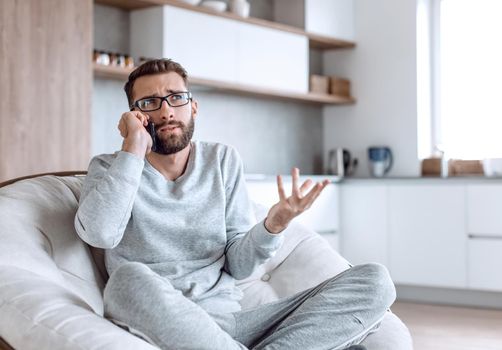 cheerful man talking on a mobile phone sitting in a comfortable chair. photo with copy space