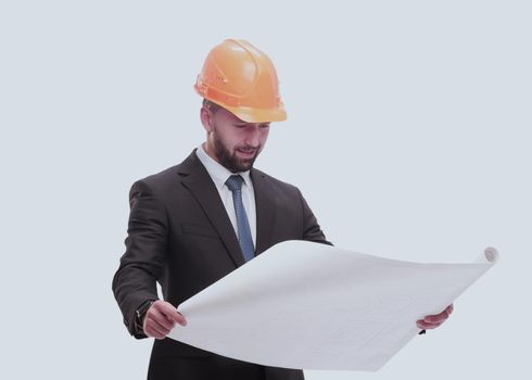 in full growth. businessman in helmet looking at new drawings . isolated on white background