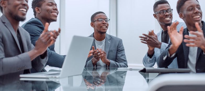 close up. business team applauds sitting at the office Desk.