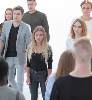 image of a serious woman standing in front of a casual group of young people.