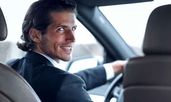 confident man sitting behind the wheel of a car