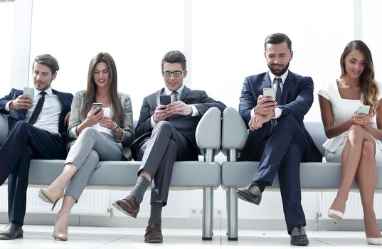 business colleagues with their smartphones sitting in the office hallway.people and technology