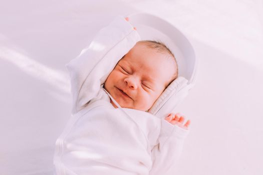 The kid is wearing headphones . Happy baby. A newborn baby. White on white