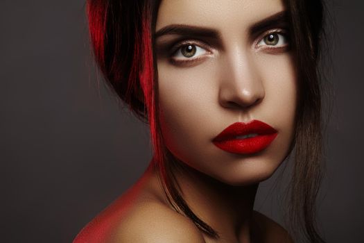 Beautiful model with fashion make-up. Sexy woman with glamour red lip makeup, strong eyebrows and bright eye shadows. Macro shot of celebrate visage, clean skin, lips with red lipstick.