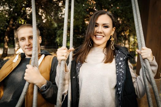 Young mixed race couple smiling happy on swing, Asian woman, Caucasian man outdoor.