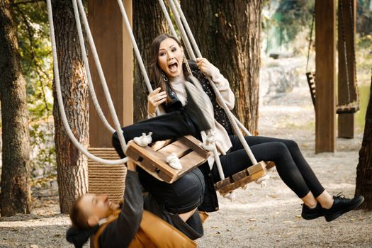 A young man on a date almost fell off a swing in the park. Shocked woman. High quality photo