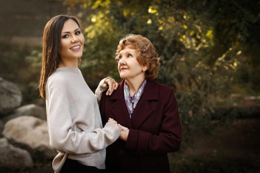 Happy mom looking at daughter holding hands outdoors in the park outdoor. High quality photo