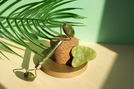 Jade Gua sha scraper and facial massager on beige background. Hard light, shadows, the concept self-care. Facial care. Zero waste. Lifting and toning treatment at home.