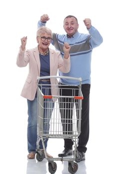 in full growth. happy married couple with shopping cart. isolated on a white background