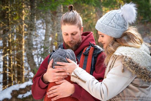 Young family with their baby are walking in the winter park.