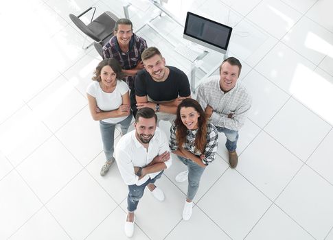 view the top. a group of young professionals standing near the desktop and looking up