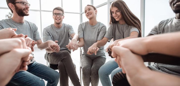 close up. a group of diverse young people holding hands