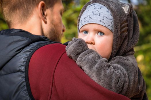 Cute baby boy walking with his dad outdoor.