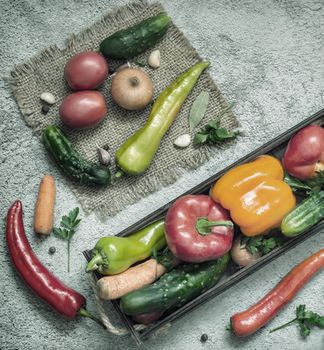 In a wooden container and on a napkin a variety of ripe vegetables: tomatoes, peppers, cucumbers, parsley, zucchini. Top view . Flat lay