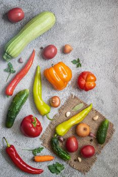 On the table and on a napkin a variety of ripe vegetables: tomatoes, peppers, cucumbers, parsley, zucchini. Top view with copy space. Flat lay