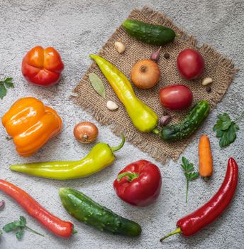 On the table and on a napkin a variety of ripe vegetables: tomatoes, peppers, cucumbers, parsley, zucchini. Top view with copy space. Flat lay