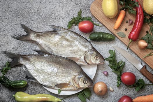 On the plate are two large bream. Nearby are vegetables and spices for cooking this river fish. Top view with copy space. Flat lay