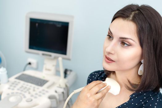 Technician diagnosing female patient using modern ultrasound scanner in diagnostic center.