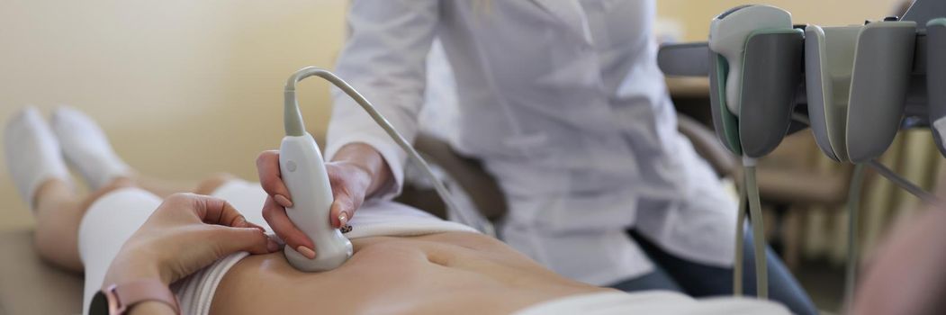 Close-up of gynecologist doing ultrasound scan in modern clinic, doctor in white lab coat examining woman. Female patient expecting pregnancy. Medicine, gynecology, health concept