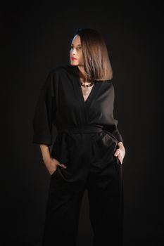 Studio shot of brunette woman 30s wearing black silk pajamas.
