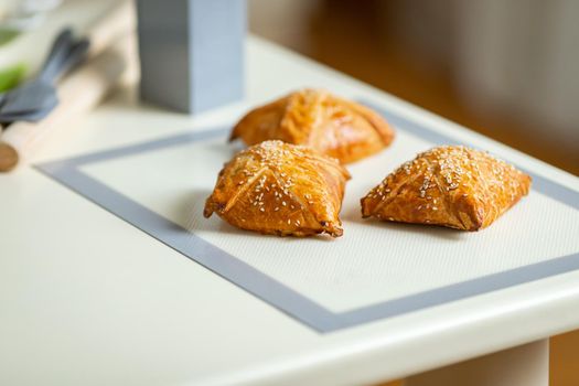 Fresh samsa on a baking mat on the kitchen table.