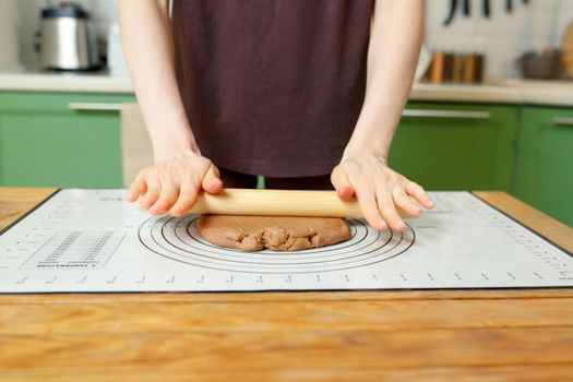 Rolling out shortcrust pastry on a silicone baking mat on a wooden table with copy space.