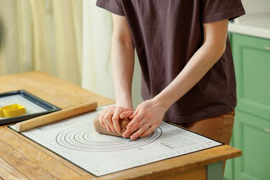 Woman hands that knead the dough for gingerbread cookies on a baking mat.