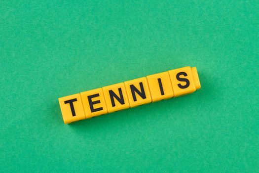 Word tennis written on yellow cubes against green background. Sport concept.
