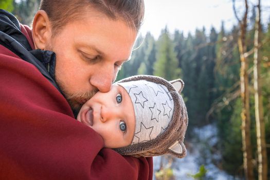 Father kisses his funny baby boy on a walk outdoor.