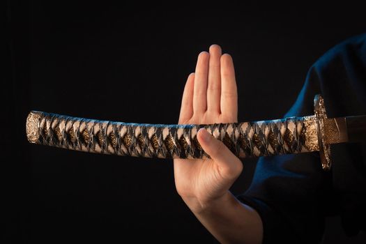 Close-up on a woman's hand with a wakizashi japanese edged weapon hilt.