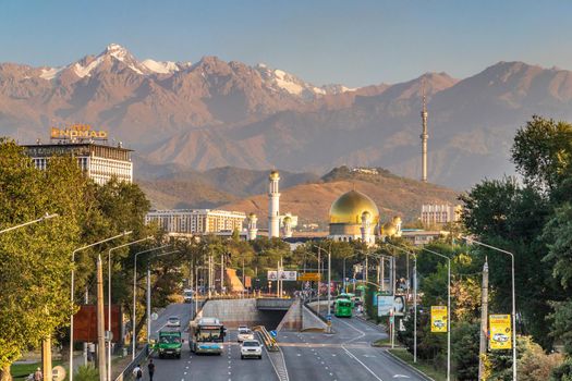 Suyunbay Avenue and the intersection with Raiymbek Street in the Sayakhat district against the backdrop of a mosque and mountains in the city of Almaty. Almaty, Kazakhstan - September, 05, 2021