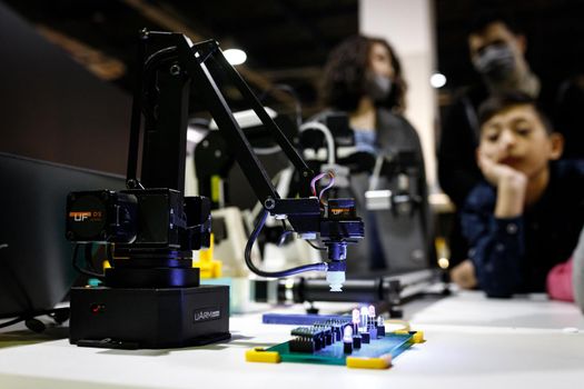 Conveyor-type robot mounting chips at the exhibition stand of the robot festival. Almaty, Kazakhstan - February 19, 2022