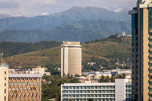 Medeu district of Almaty city with the GATOB theater and the famous hotel Kazakhstan against the backdrop of the Almaty mountains. Almaty, Kazakhstan - July, 02, 2021