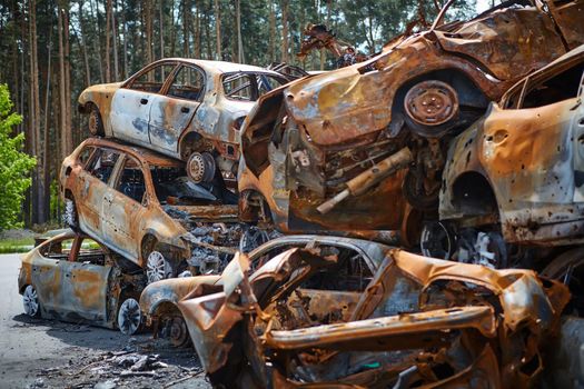 A lot of rusty burnt cars in Irpen, after being shot by the Russian military. Russia's war against Ukraine. Cemetery of destroyed cars of civilians who tried to evacuate from the war zone.
