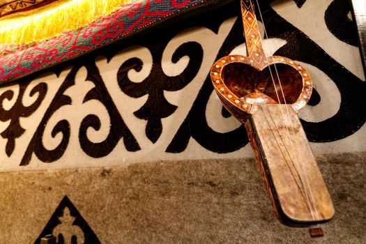 Kobyz, kazakh national musician instrument, on the background of a carpet with Kazakh ornament, copy space.