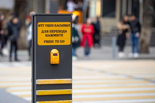 Button for turning on the green light of a traffic light at a pedestrian crossing. Almaty, Kazakhstan - March 21, 2021