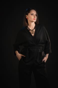 Brunette woman posing in black silk kimono on a black background.
