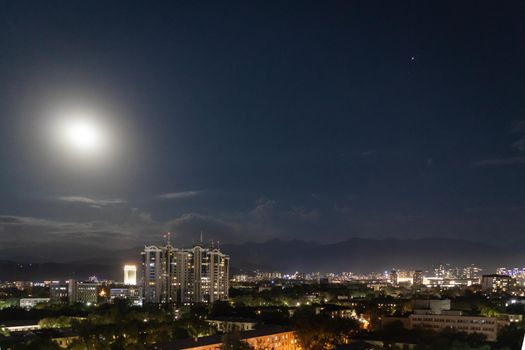 Night view of the central district of the city of Almaty with the moon in the sky. Almaty, Kazakhstan - September, 21, 2021