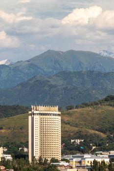 Vertical view of the Medeu district of Almaty city with the GATOB theater and the famous hotel Kazakhstan against the backdrop of the Almaty mountains. Almaty, Kazakhstan - July, 02, 2021