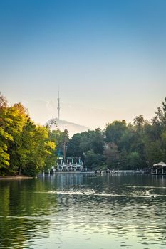 Autumn landscape of a small lake in the center of Almaty park against the background of the TV tower on Kok-Tobe. Almaty, Kazakhstan - Oktober, 14, 2021