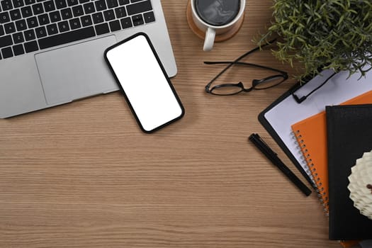 Simple workplace with laptop computer, mobile phone, glasses and coffee cup. Top view.