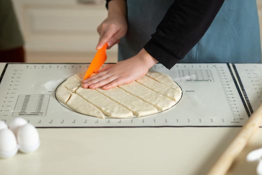 Cutting dough with a plastic knife on a silicone baking mat.