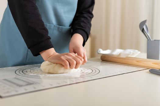 The hands of the cook knead the wheat dough on a rubber kitchen mat with different markings for ease of use.