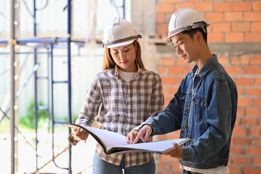 Young engineers supervising progress of construction project together. Industry, Engineer, construction concept.