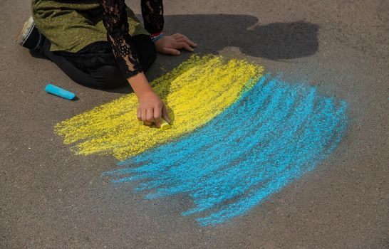 Children draw the Ukrainian flag on the pavement. Selective focus. Nature.