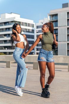 vertical photo of two young african friends stroll happy holding hands in the city, concept of friendship and urban lifestyle