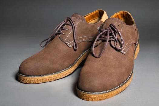 Casual brown shoes with laces on a gray background.