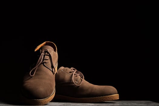 Elegant brown shoes with laces on a black background with copy space