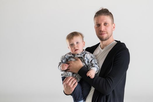 Young caucasian father holding a baby in his arms on a white background.